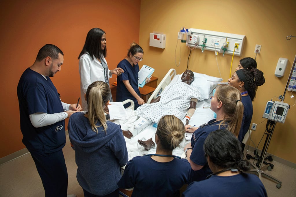 Multiple Utica students observing vitals in a clinical setting