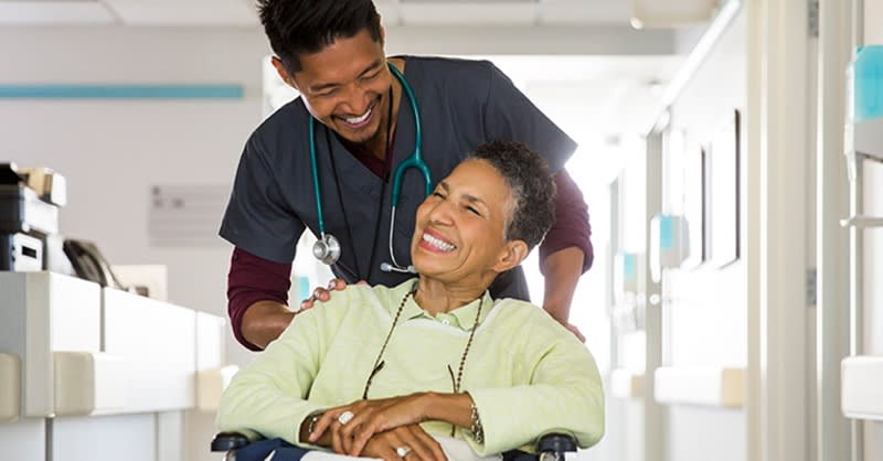 Nursing student pushing woman in wheelchair in hospital setting