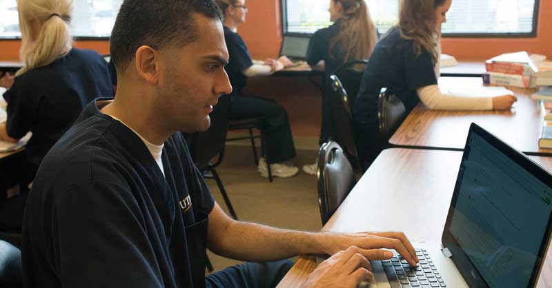 Utica ABSN student using computer at desk