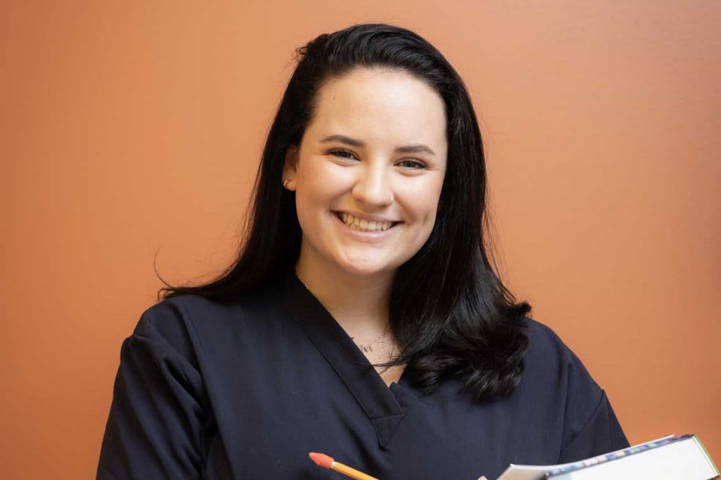 Utica nursing student smiling holding book