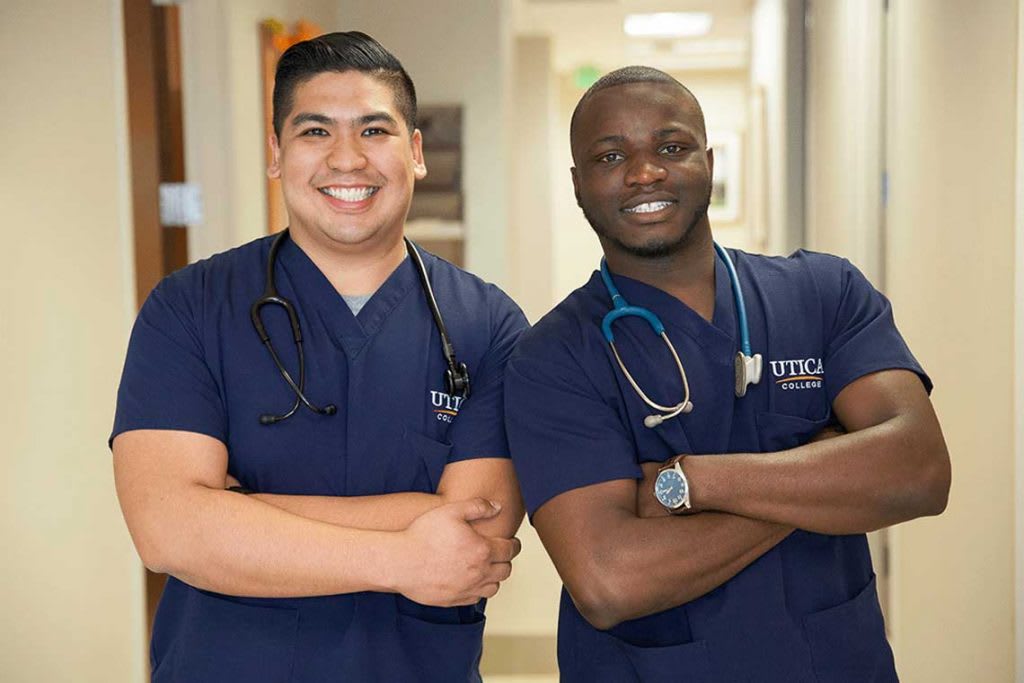 2 Utica nursing students smiling with their arms crossed