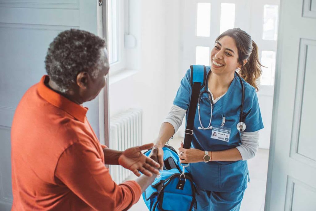 nurse shaking hand of patient while entering home