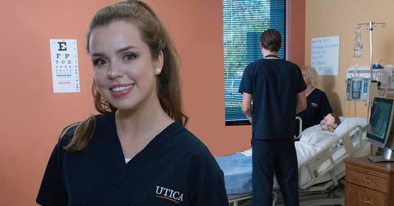 Utica ABSN student standing and smiling in simulation lab