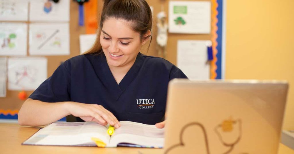 nursing student studying with book and laptop