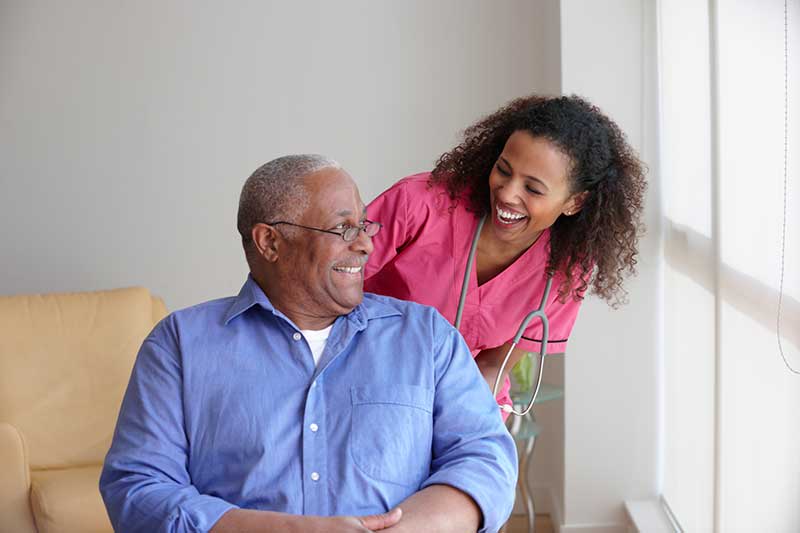 nursing home nurse smiling at older patient