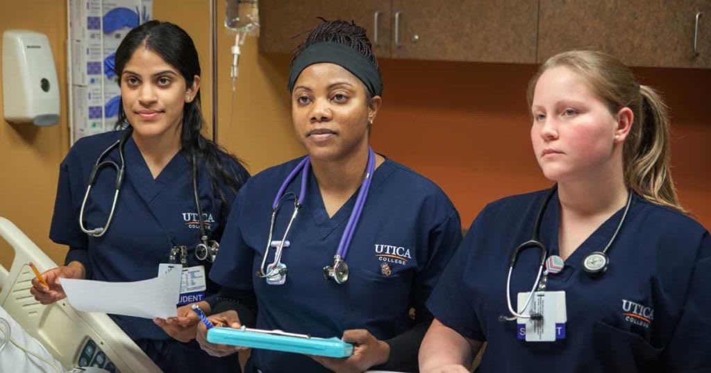 three nursing students standing by patient bed