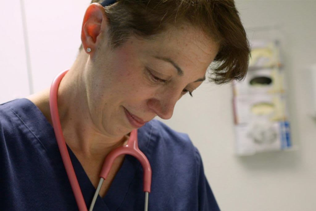 Xavier absn student looking down ins stethoscope