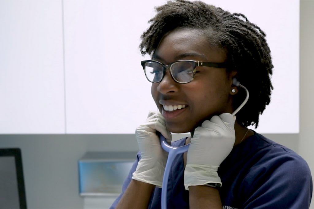 xavier absn student listening in stethoscope