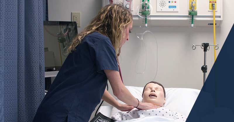 Xavier ABSN student working with sim manikin