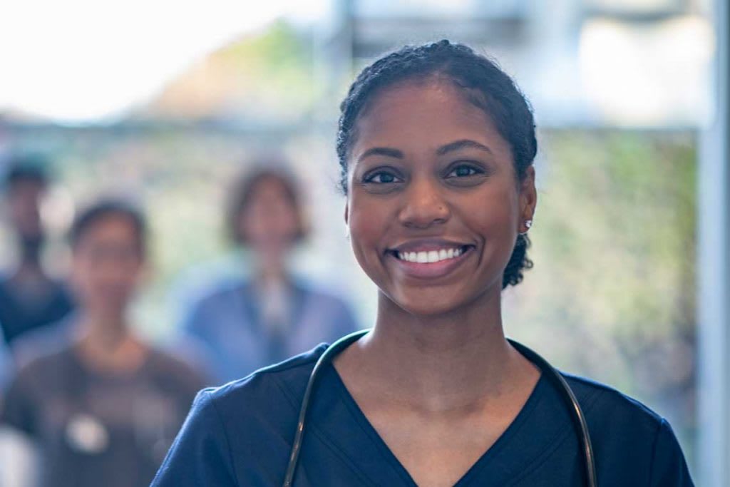 smiling nurse with other nurses standing in background