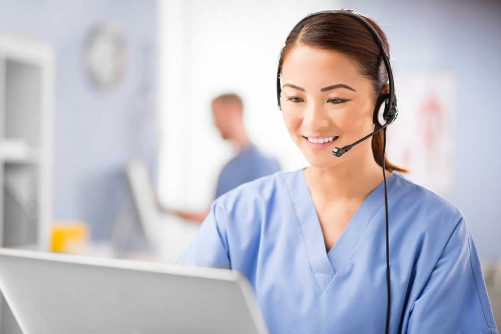 nurse sitting at desk with computer and headset