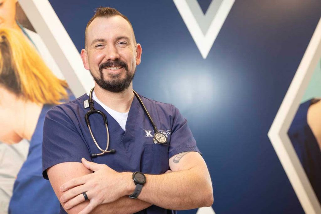 nursing student in front of Xavier wall smiling at camera