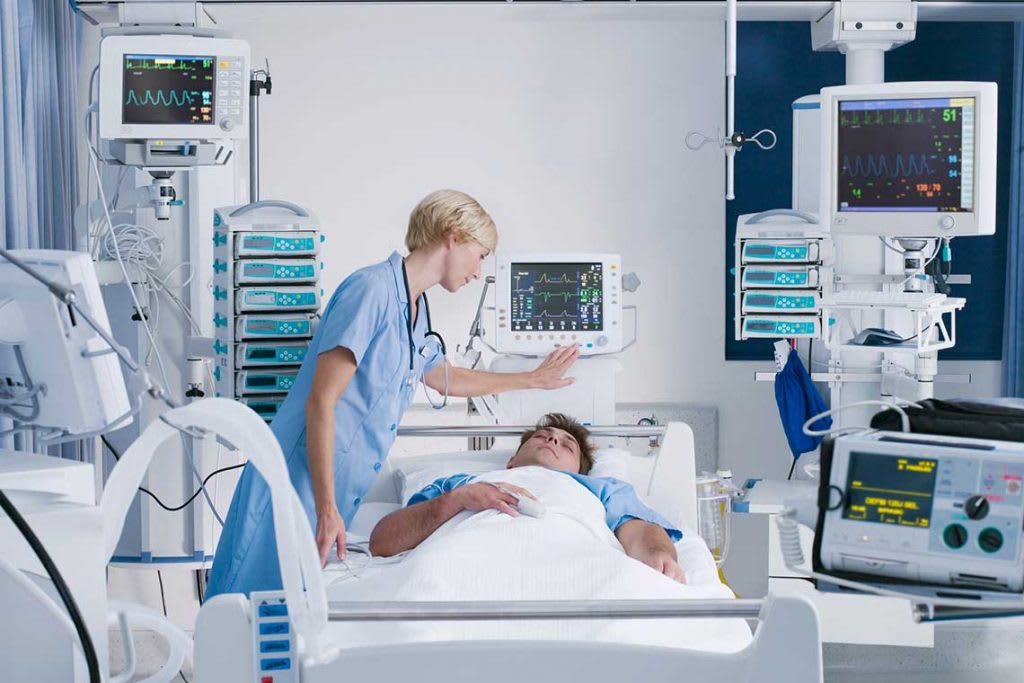 a nurse using monitor above patient's bed