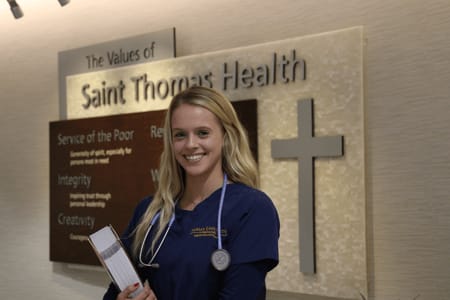 Shelbi in front of a Saint Thomas Health sign