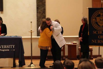 Man in lab coat hugging woman at Marian University event