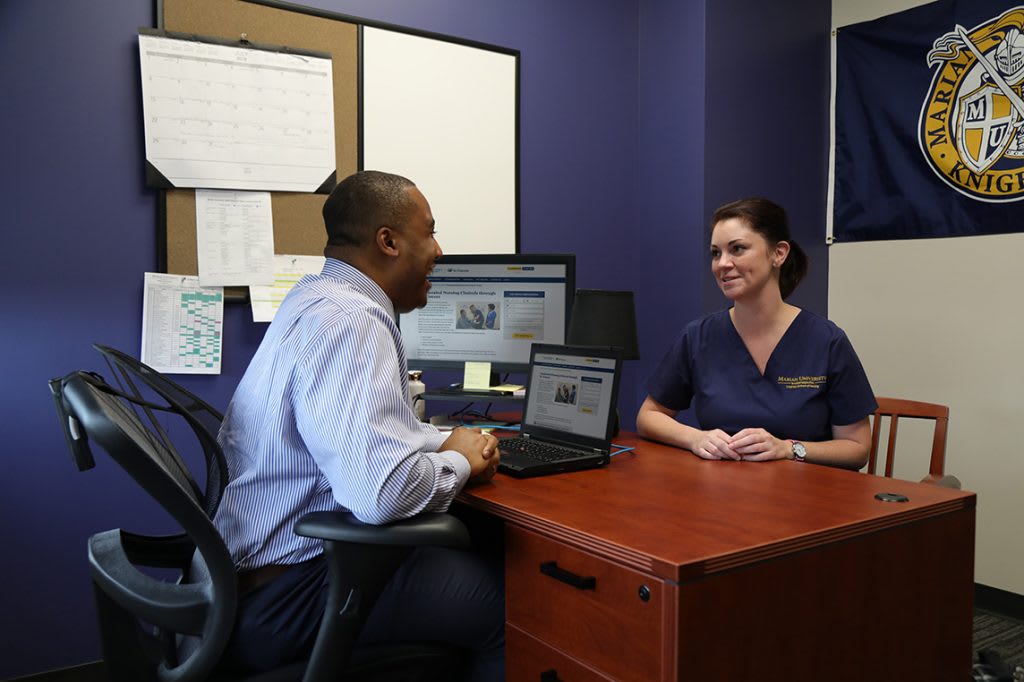 nursing student sitting at desk with admissions counselor