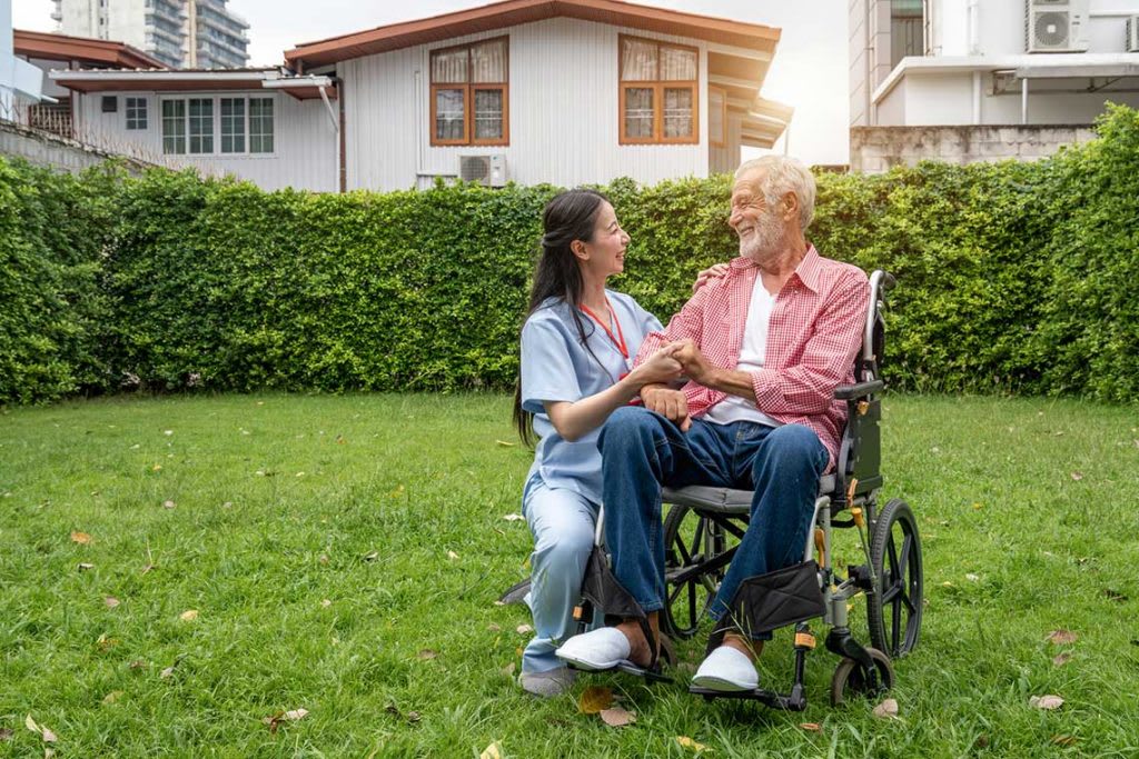 nurse in courtyard with patient in wheelchair