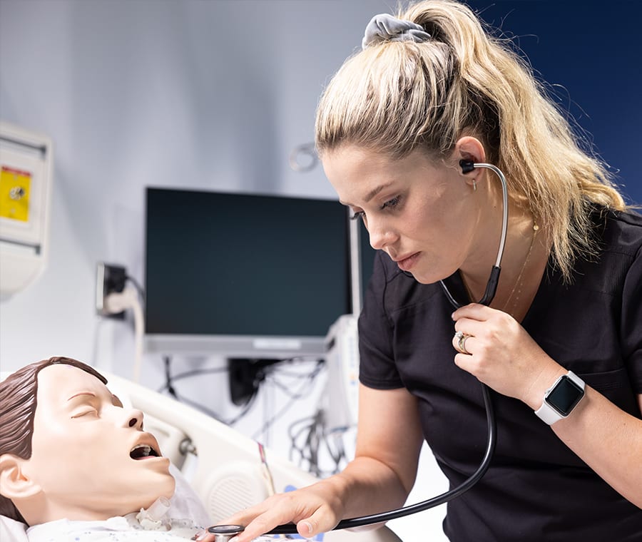 nursing student using stethoscope on manikin