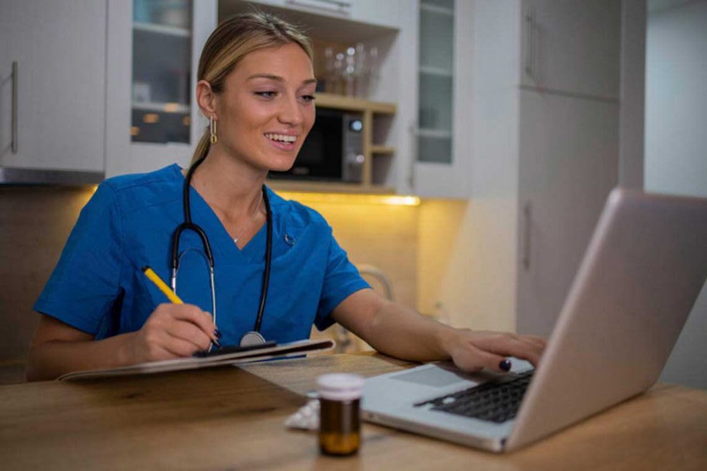 nursing student sitting at table using laptop