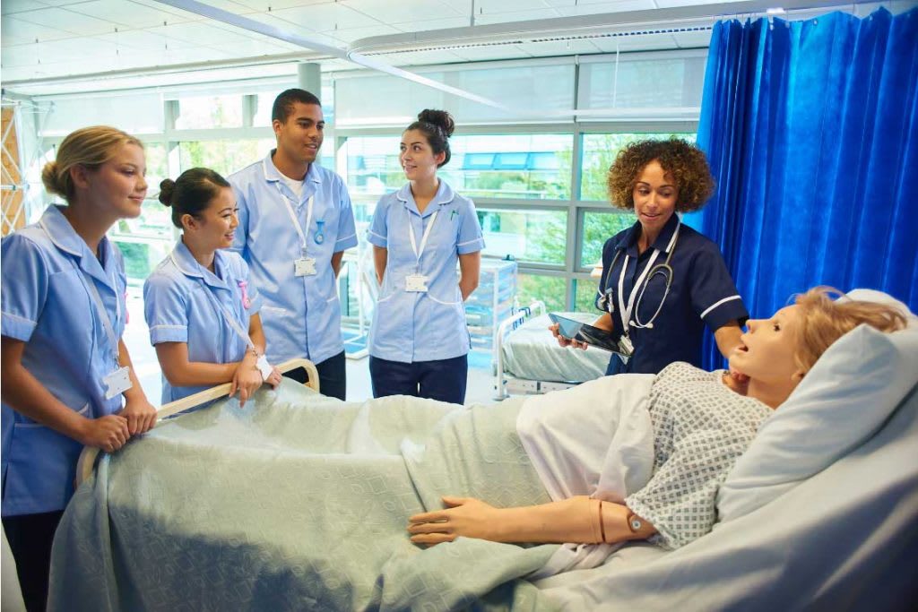 nurses standing in simulation lab next to manikin