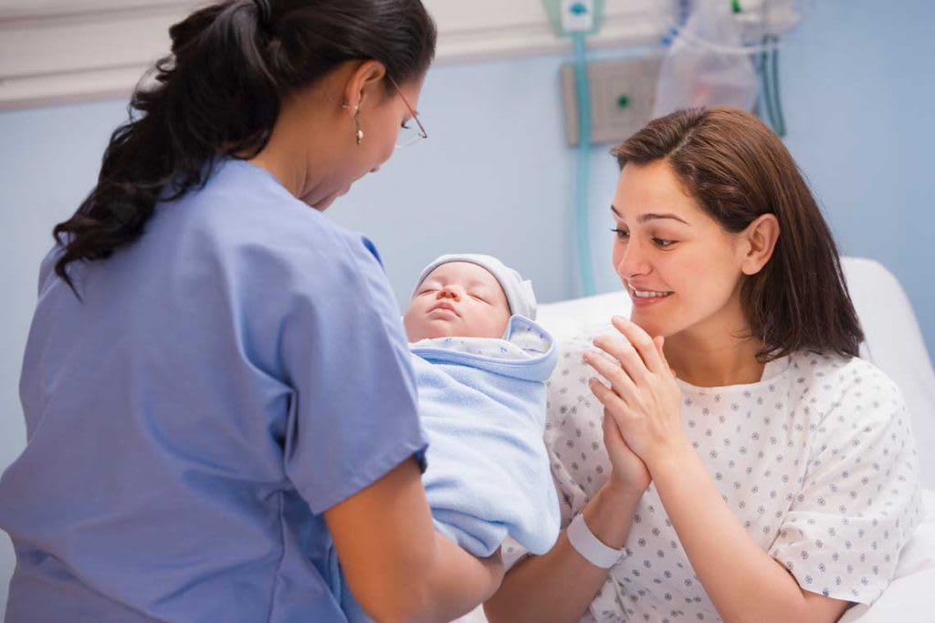 nurse handing baby to mother