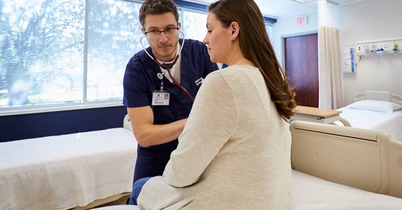 A male marquette student checking the heartbeat of a patient during clinical