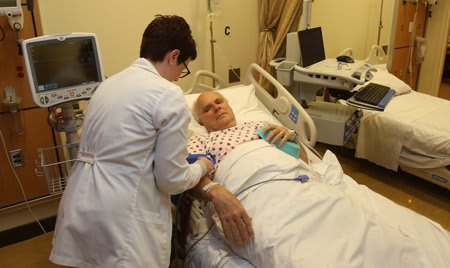 nursing student standing over patient