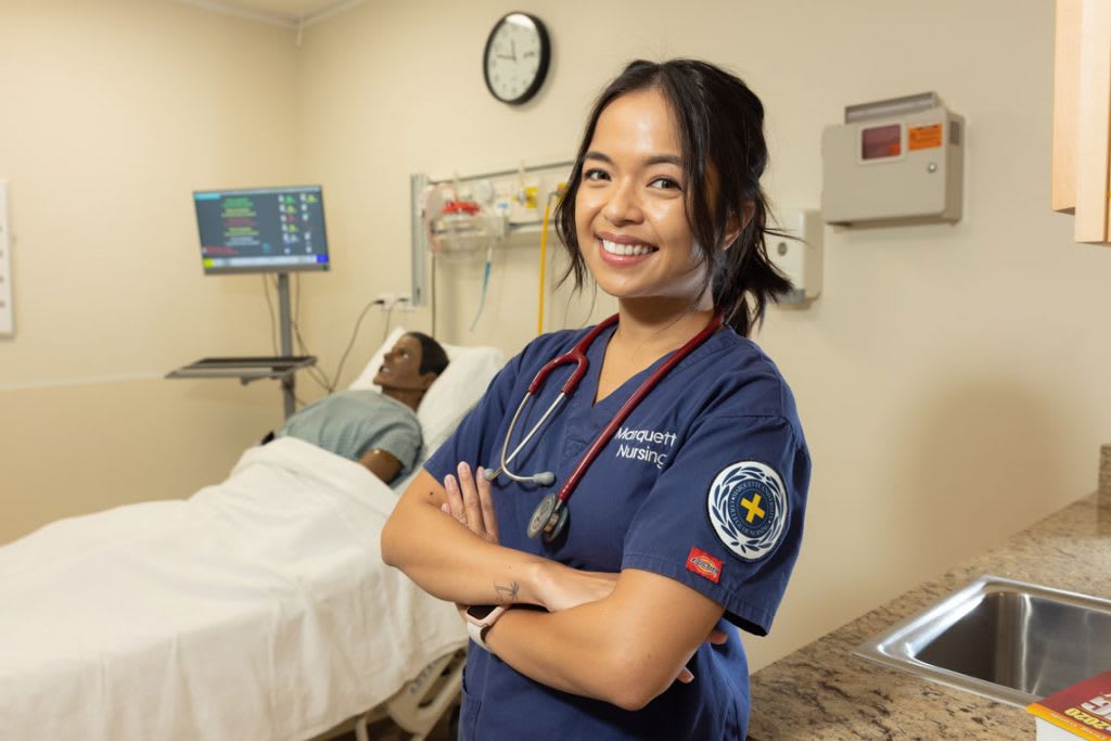 nursing student smiling with manikin in the back