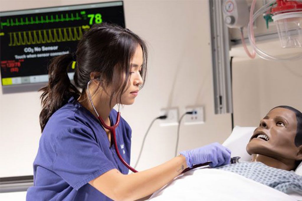 Nursing student with stethoscope and manikin
