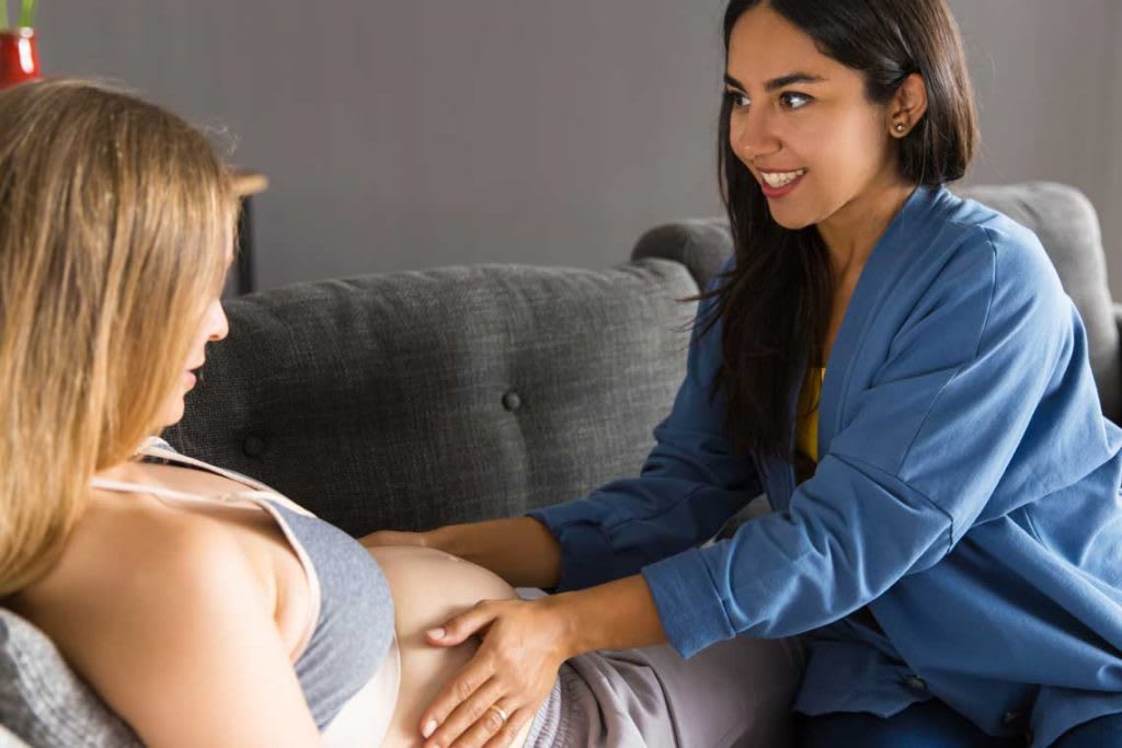 midwife touching pregnant woman's stomach