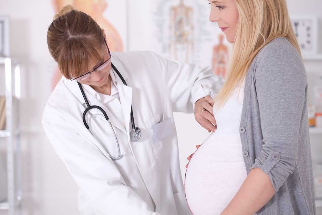 nurse midwife helping pregnant patient