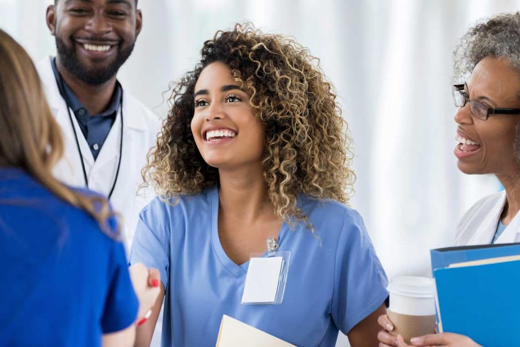 nurse smiling and shaking hands with coworkers