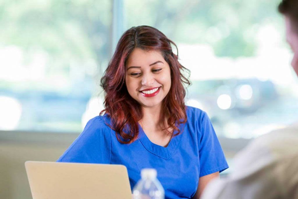 nurse looking at laptop smiling