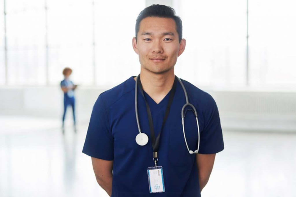 nurse standing arms behind back smiling at camera