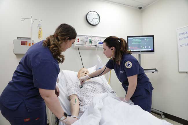 Two Marquette students examining a simulation manikin