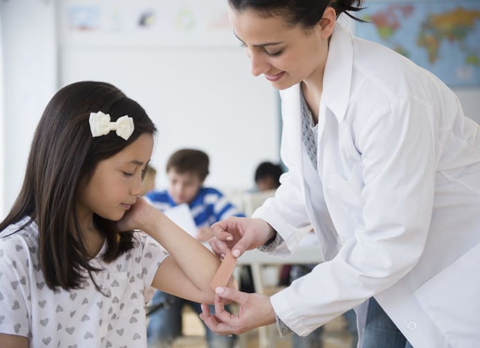 School nurse putting band aid on child's elbow