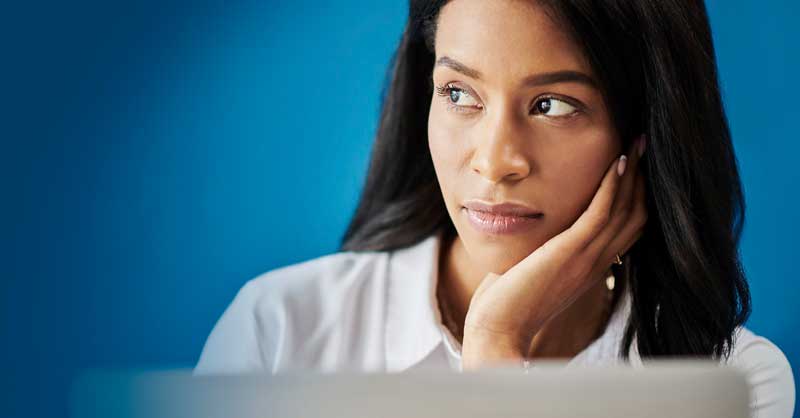 woman sitting behind computer thinking