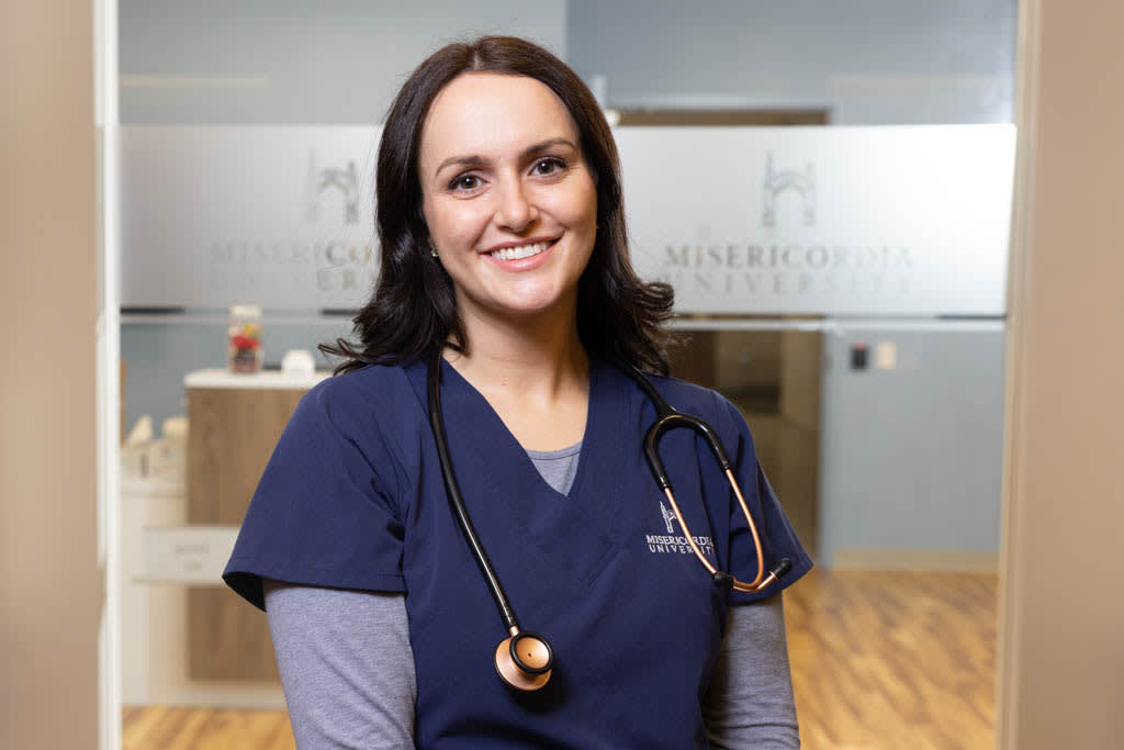 nursing student in front of MIS doors smiling at camera