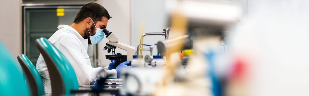 Medical laboratory science student looking into microscope