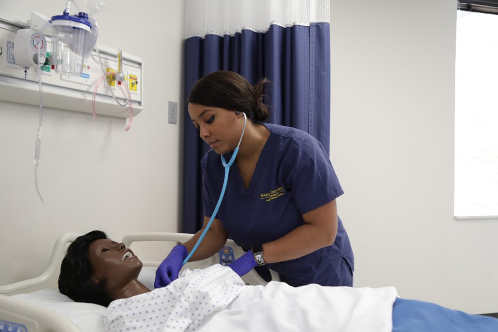 Marian ABSN student using stethoscope on a sim manikin