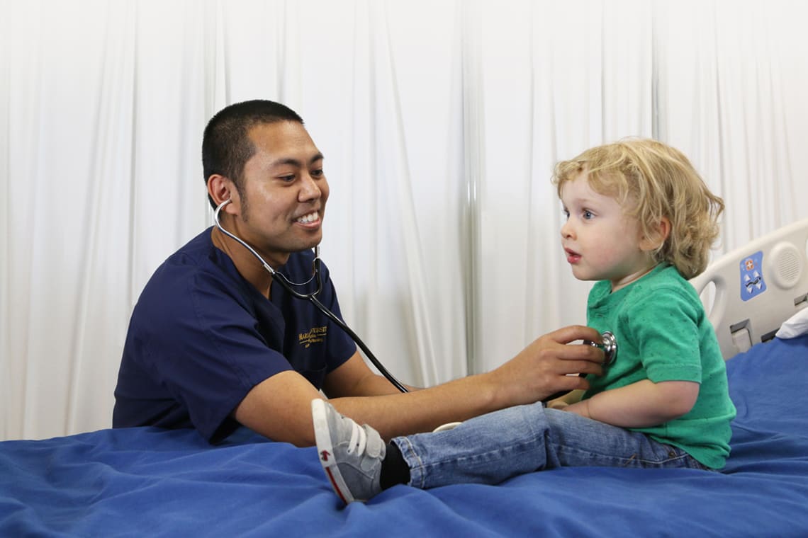 nursing student listening to child patient's heartbeat