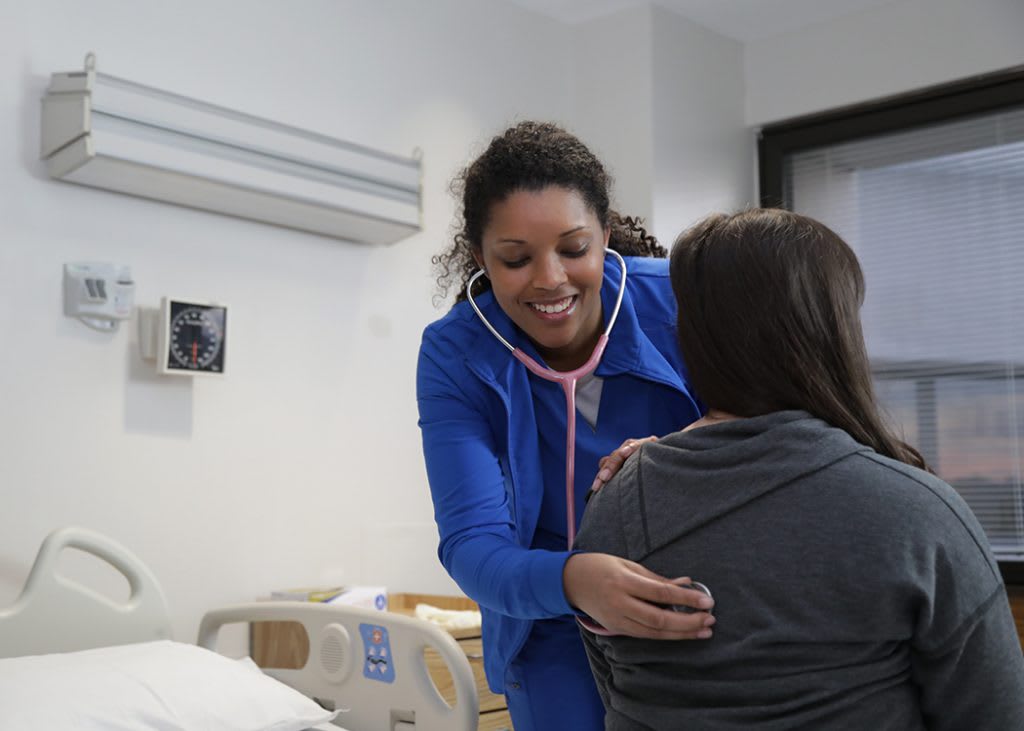 a Marian ABSN student using stethoscope with patient in room