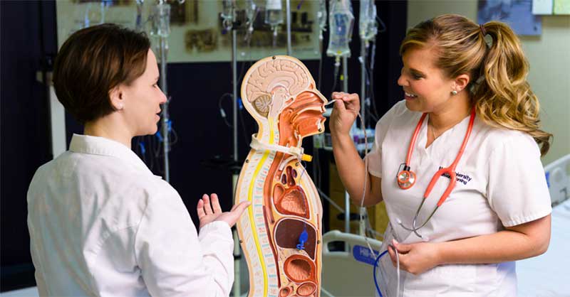 an ABSN student with instructor in skills lab