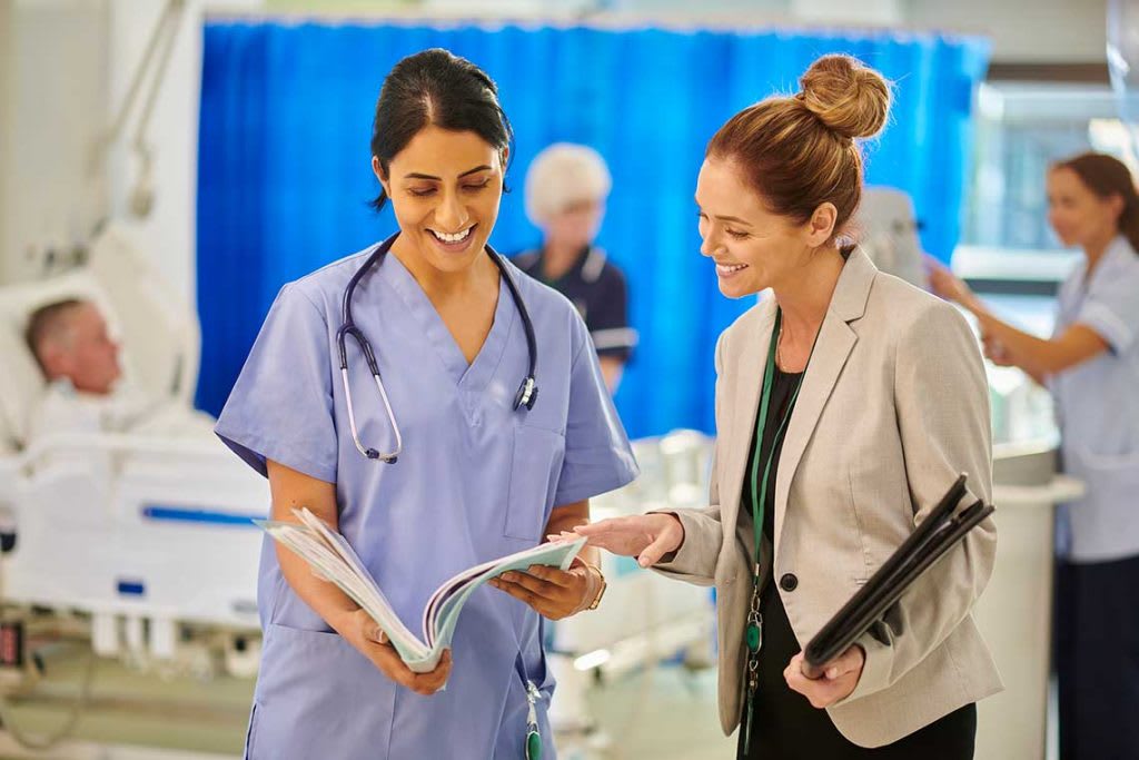 nurse manager helping nurse in patient room