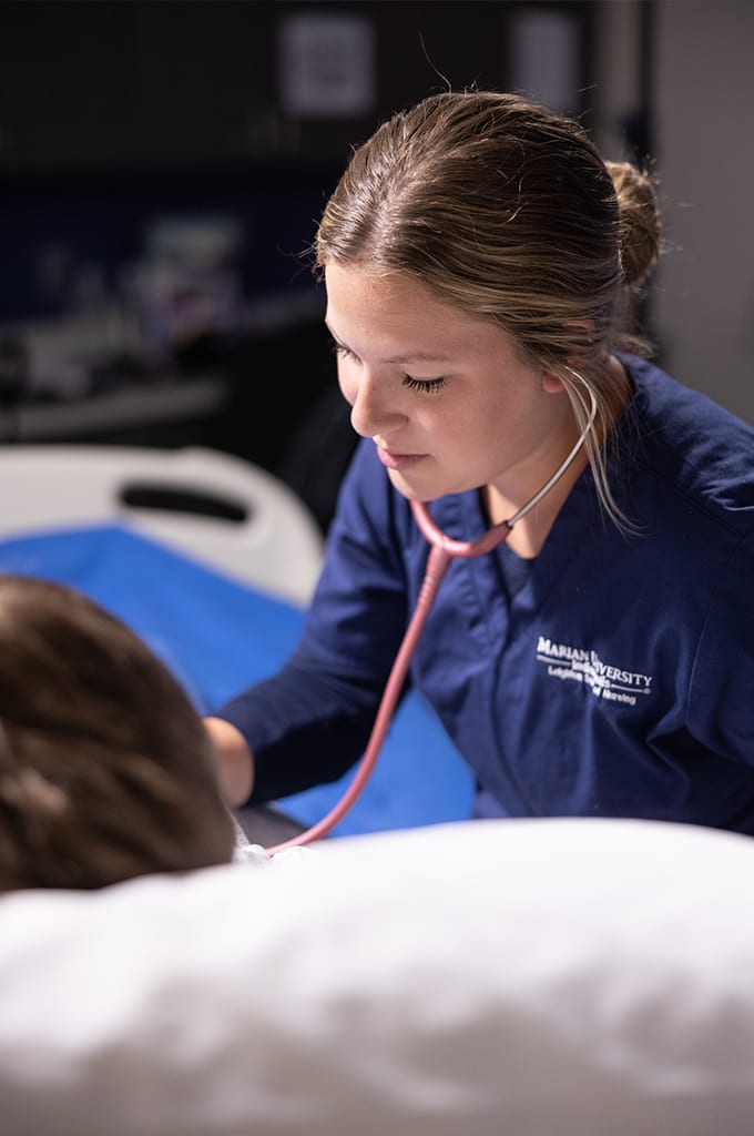 nurse with stethoscope over manikin