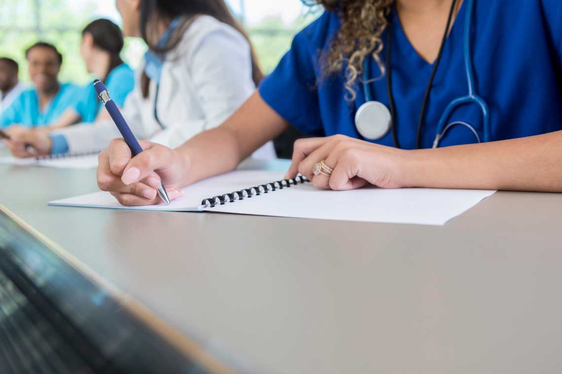 Nurses in class writing in notebooks