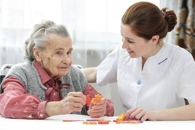 Woman assisting elderly woman with a puzzle