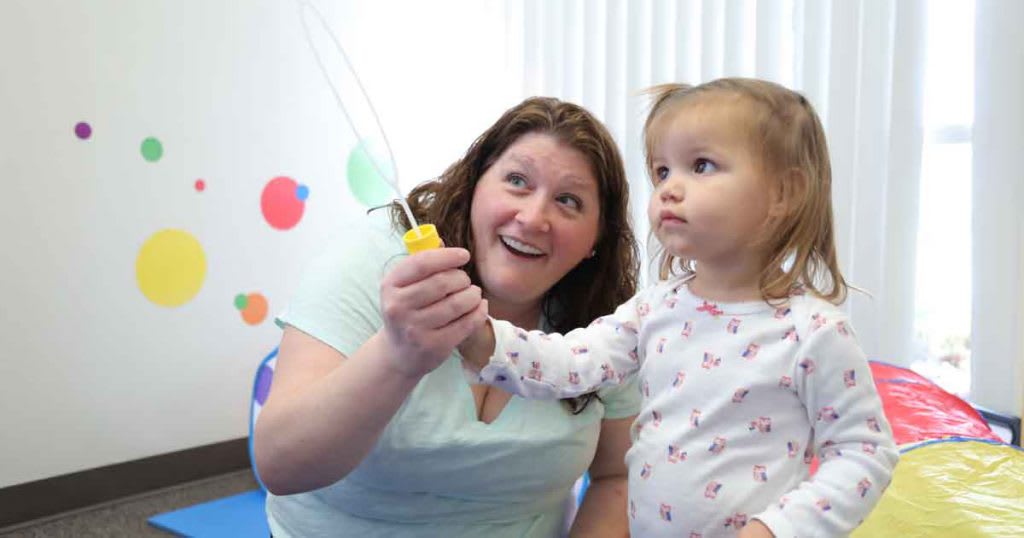 adult helping child holding bubble wand