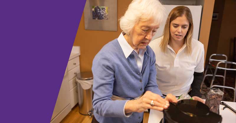 woman helping elderly woman in kitchen