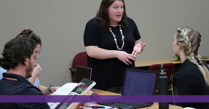Woman standing talking to three students